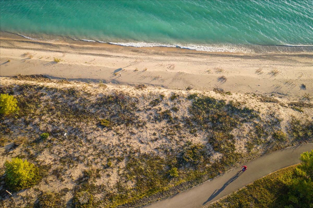 A bike rider on a the Huron Sunrise Trail adjacent to the blue/green water of Lake Huron just north of Rogers City